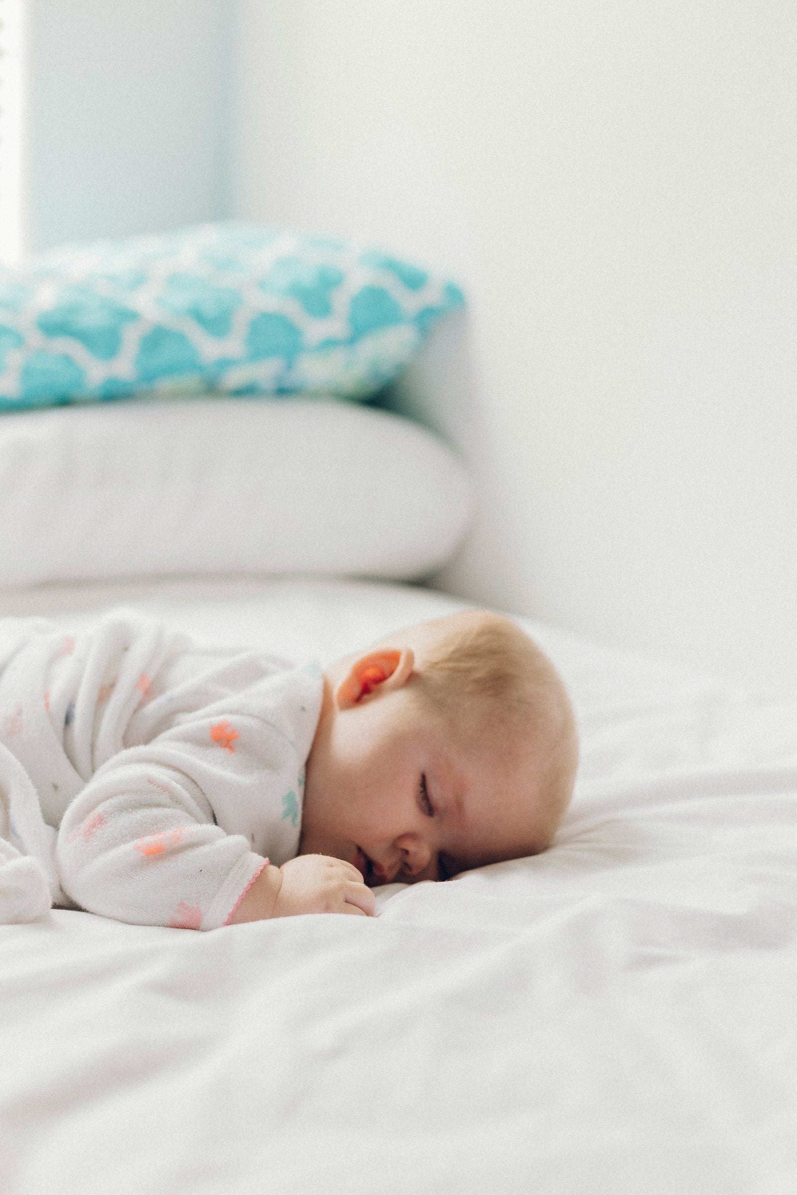 Ein Baby schläft auf einem Bett mit Kissen im Hintergrund