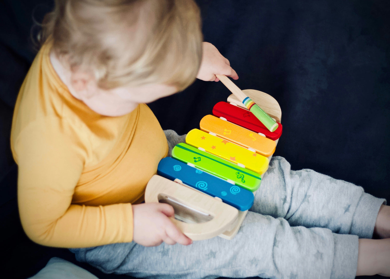 Ein Kleinkind spielt auf einem regenbogenfarbenem Xylophon