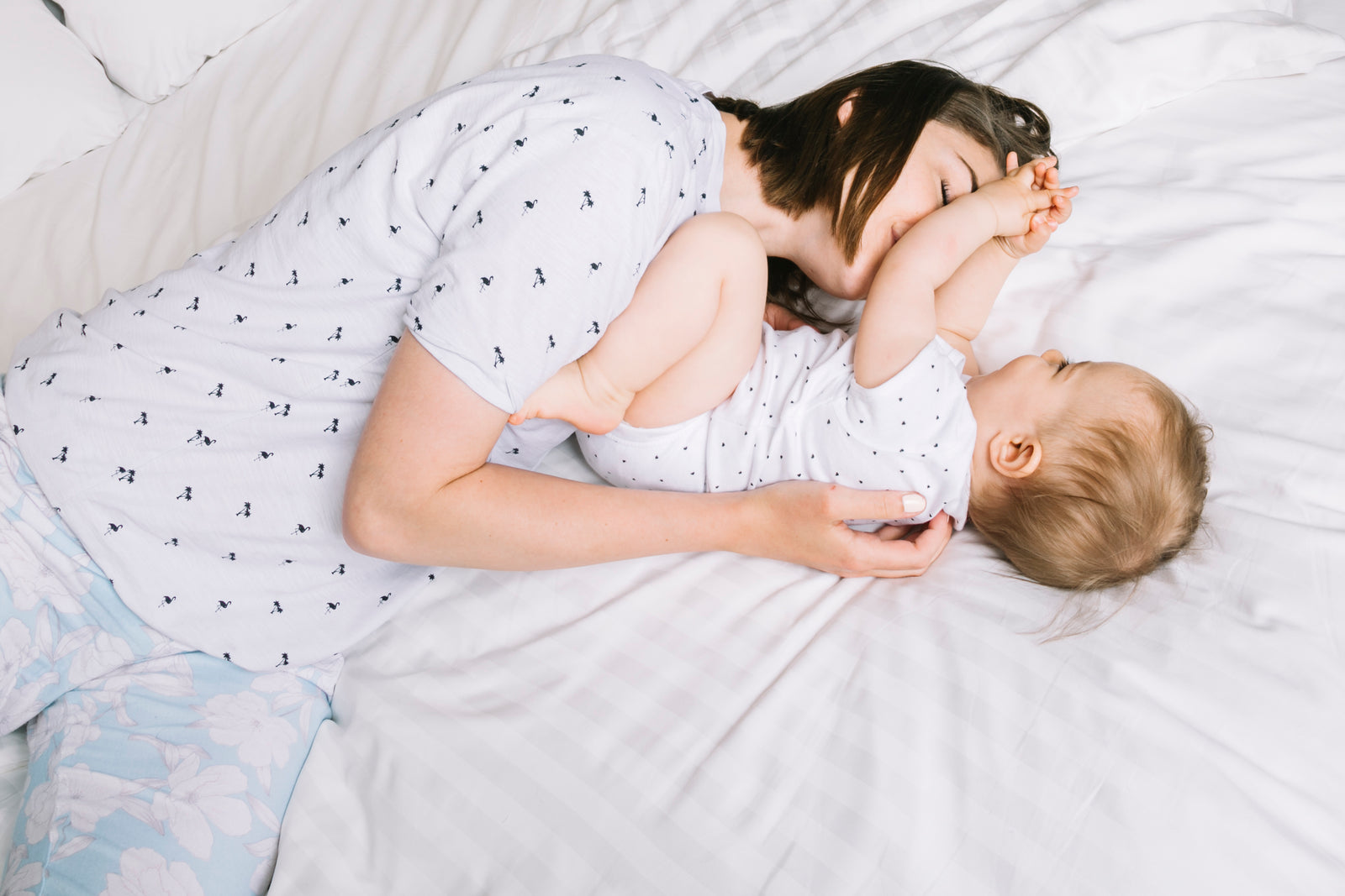 Eine Mutter kuschelt mit ihrem Baby im Bett