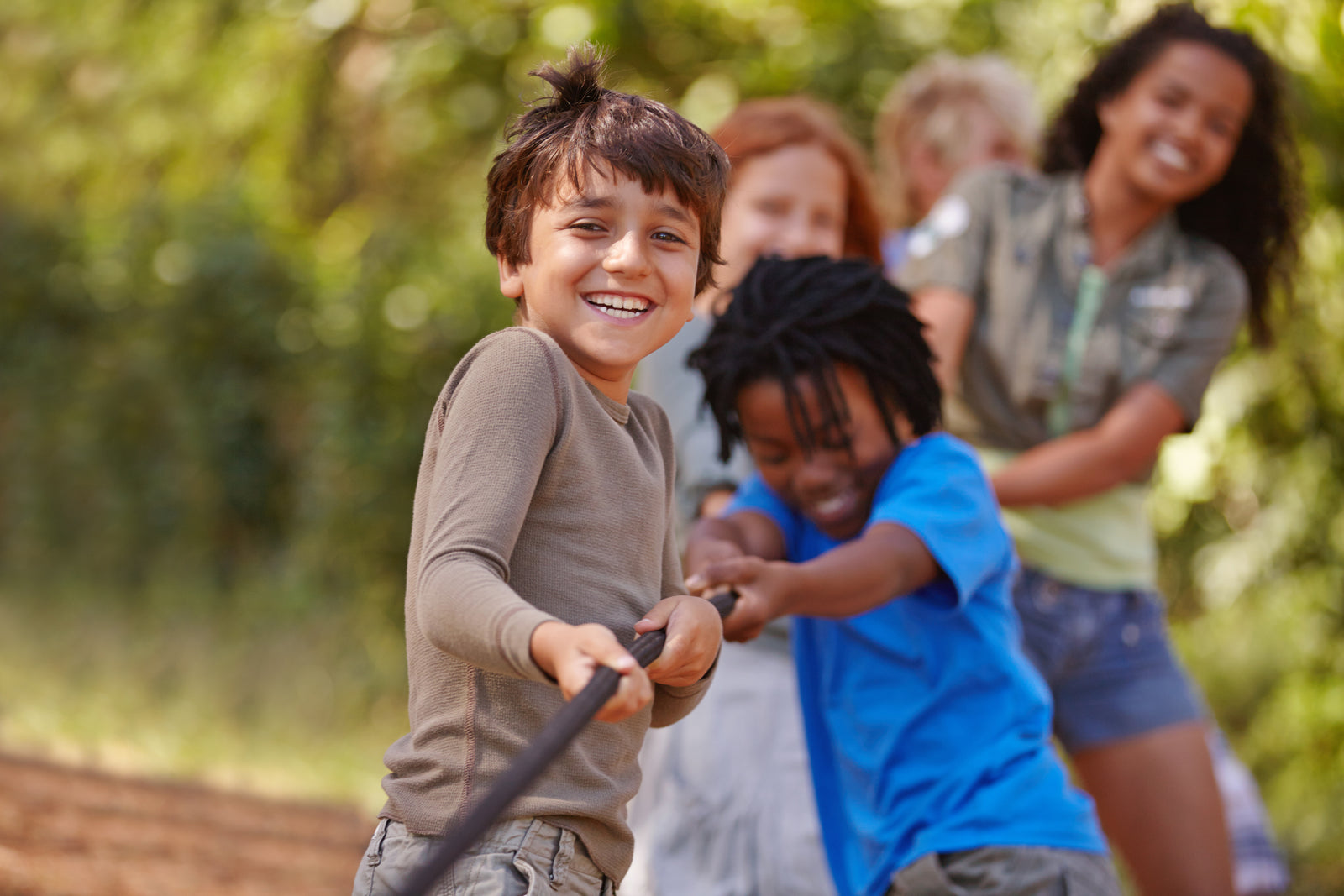 Fünf Kinder ziehen gemeinsam an einem Tau im Freien